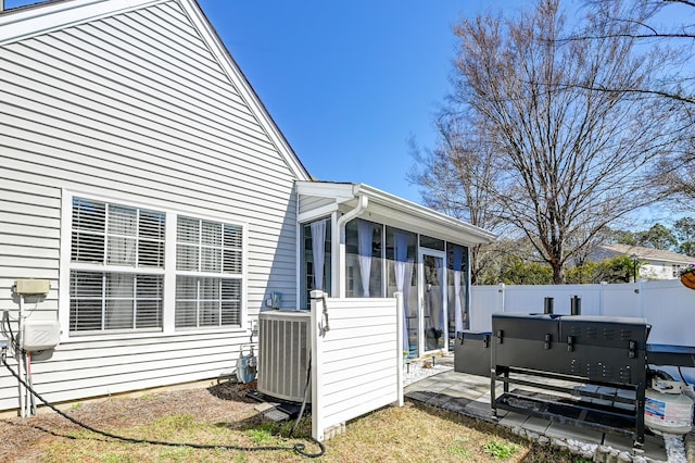 back of property with central AC unit, fence, a sunroom, and a hot tub