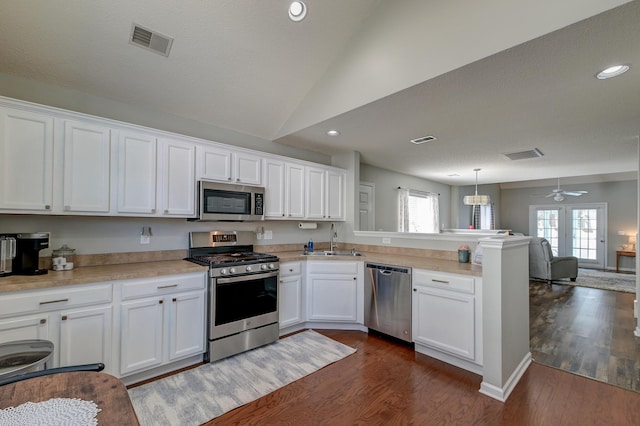 kitchen featuring visible vents, appliances with stainless steel finishes, open floor plan, a sink, and a peninsula