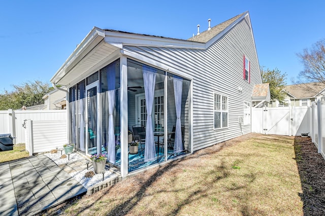 view of property exterior featuring a lawn, a sunroom, a gate, a patio area, and a fenced backyard