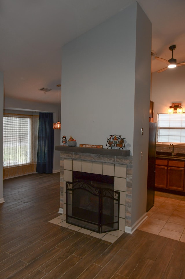 living room with a tiled fireplace, a wealth of natural light, and wood-type flooring