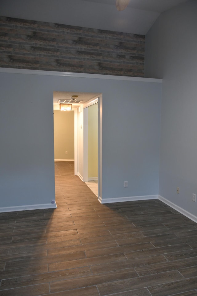 spare room featuring dark wood-type flooring and vaulted ceiling