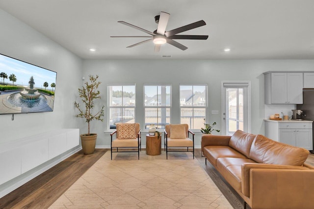 living room featuring ceiling fan, baseboards, light wood-style flooring, and recessed lighting