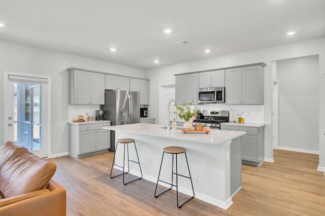 kitchen featuring appliances with stainless steel finishes, visible vents, light wood-style flooring, and gray cabinetry