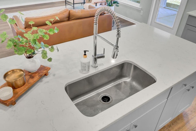 room details with wood finished floors, a sink, and light stone countertops