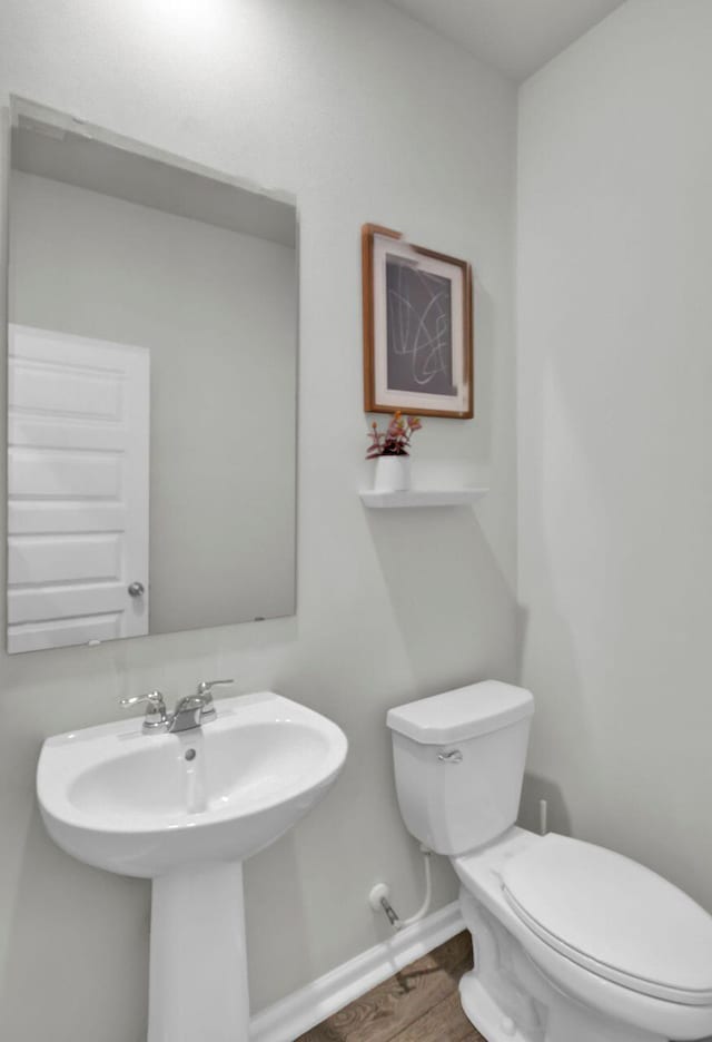 bathroom featuring a sink, wood finished floors, toilet, and baseboards