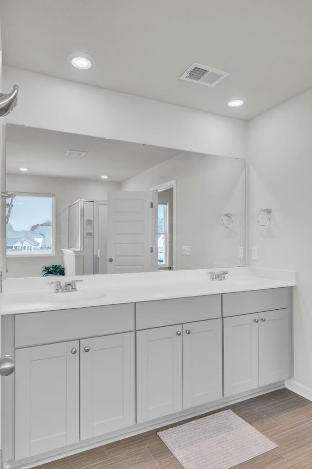 full bathroom featuring double vanity, wood finish floors, a sink, and visible vents