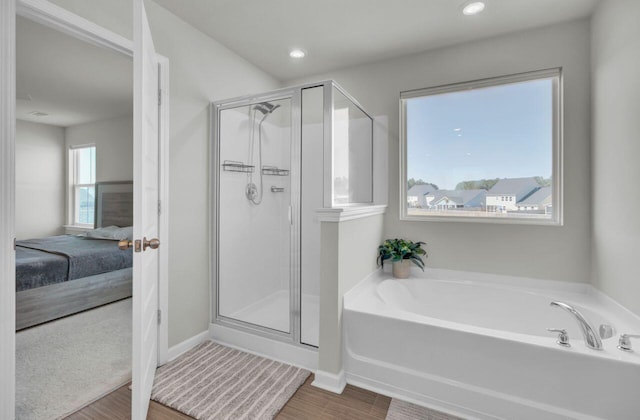 ensuite bathroom featuring wood finished floors, a shower stall, a bath, and ensuite bathroom