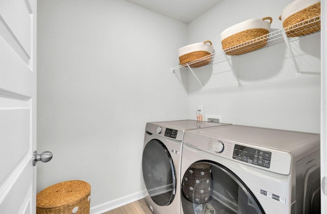 laundry area featuring laundry area, baseboards, separate washer and dryer, and light wood-style floors