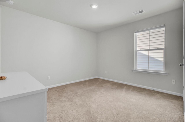 empty room with light colored carpet, visible vents, and baseboards