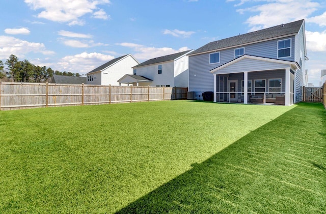 back of property with a lawn, a fenced backyard, and a sunroom