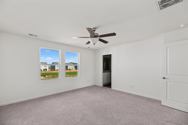 carpeted empty room with visible vents, ceiling fan, and baseboards