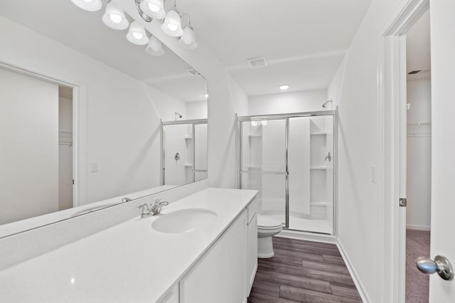 full bath featuring a walk in closet, visible vents, toilet, a shower stall, and wood finished floors