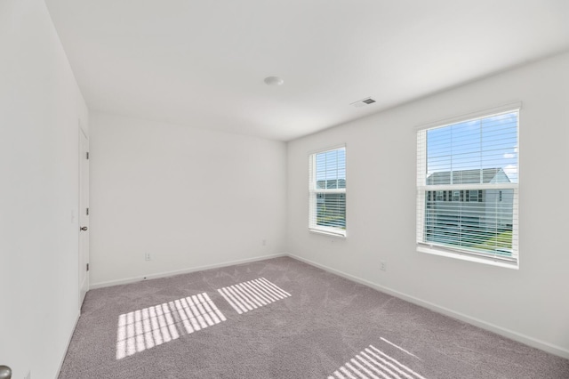 unfurnished room with carpet flooring, visible vents, and baseboards