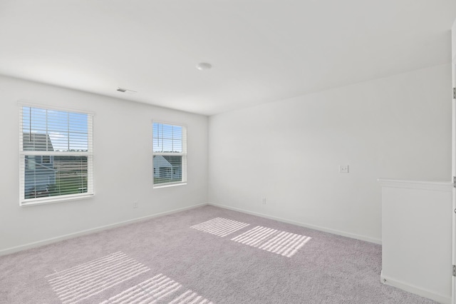 spare room with carpet floors, baseboards, and visible vents