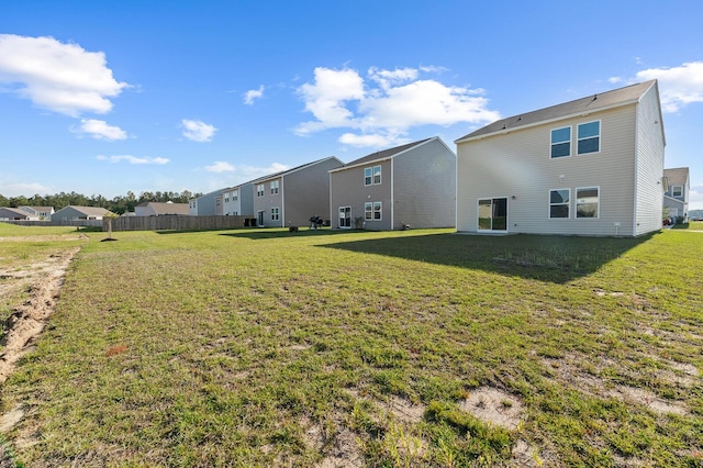 rear view of property with a residential view, fence, and a lawn