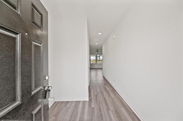 corridor with light wood-style flooring and baseboards