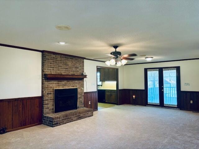 unfurnished living room featuring light carpet, wood walls, a brick fireplace, and ceiling fan