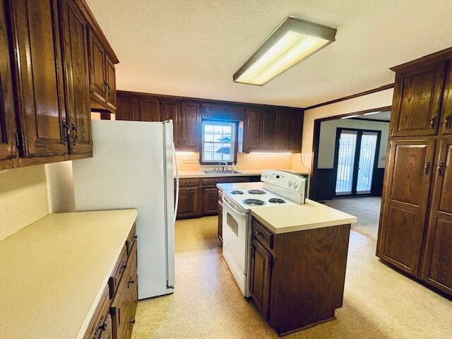 kitchen featuring ornamental molding, sink, a center island, dark brown cabinetry, and white appliances