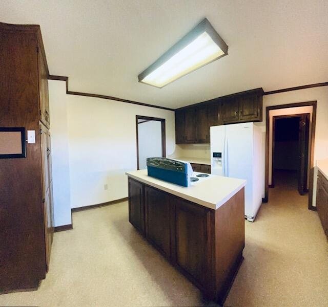 kitchen with light carpet, ornamental molding, a center island, dark brown cabinetry, and white refrigerator with ice dispenser