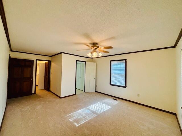 unfurnished bedroom with light carpet, crown molding, a textured ceiling, and ceiling fan