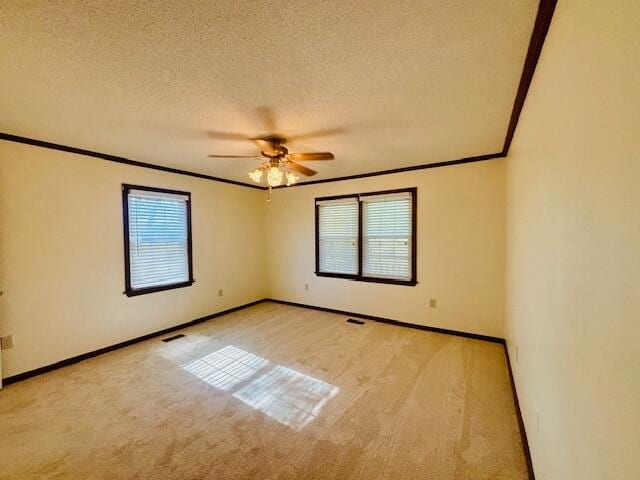 spare room with ceiling fan, crown molding, a textured ceiling, and light colored carpet