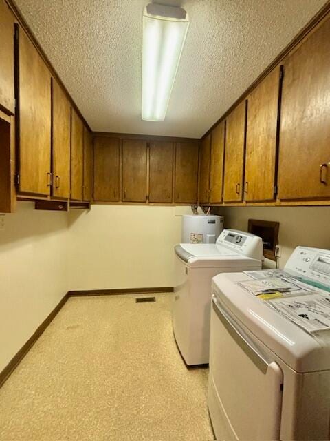 clothes washing area featuring cabinets, a textured ceiling, electric water heater, and washing machine and dryer