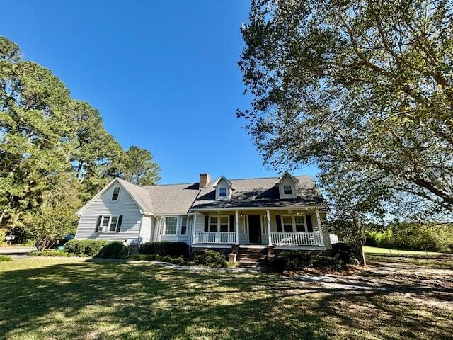 cape cod-style house featuring a front yard and covered porch