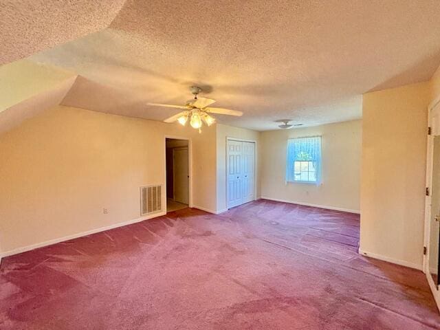 additional living space featuring vaulted ceiling, carpet flooring, and a textured ceiling