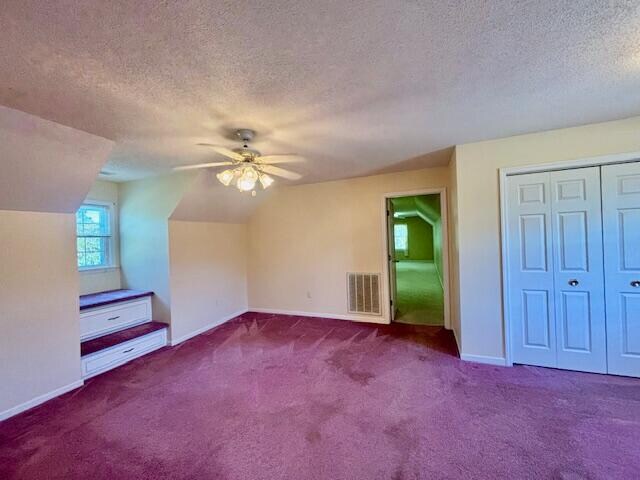 bonus room with carpet flooring, vaulted ceiling, a textured ceiling, and ceiling fan