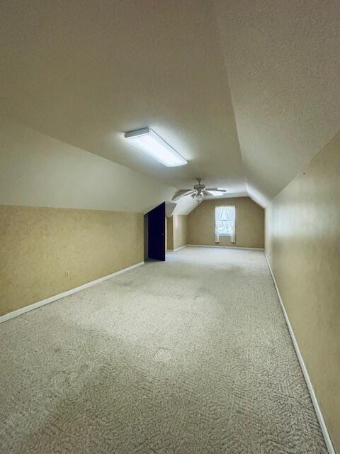 additional living space with a textured ceiling, ceiling fan, carpet flooring, and vaulted ceiling