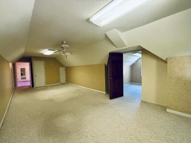 bonus room with lofted ceiling, light carpet, a textured ceiling, and ceiling fan