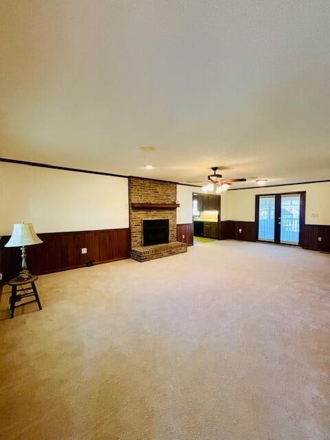 unfurnished living room featuring a brick fireplace, light colored carpet, and wood walls