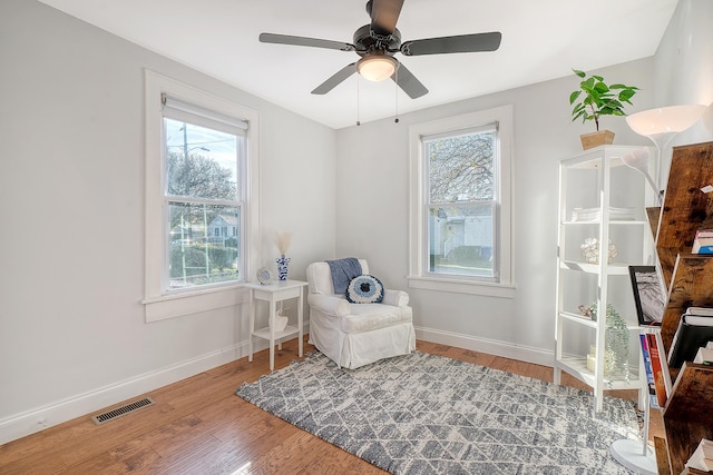 living area featuring hardwood / wood-style floors, ceiling fan, and a healthy amount of sunlight