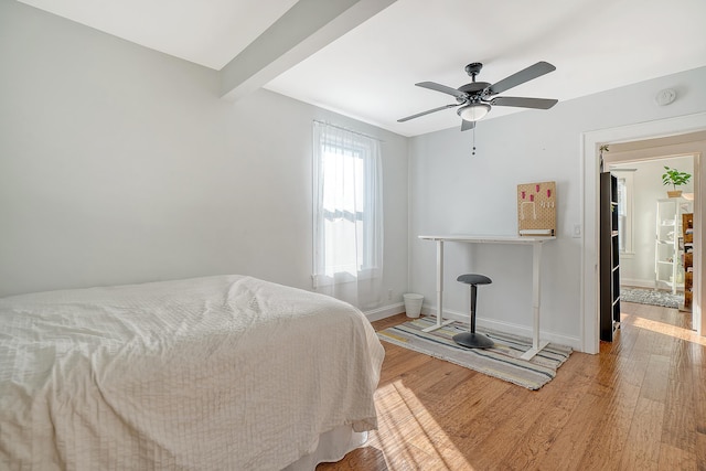 bedroom with beamed ceiling, light wood-type flooring, and ceiling fan