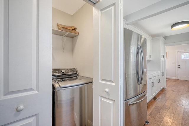 laundry area with light wood-type flooring and washer / dryer