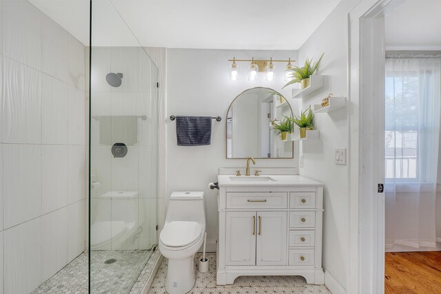 bathroom with tiled shower, vanity, and toilet