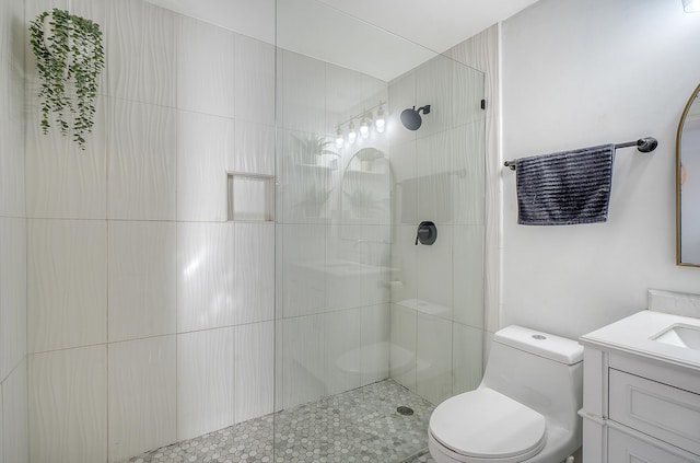 bathroom with vanity, toilet, and tiled shower