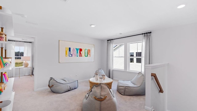 sitting room featuring an upstairs landing, light colored carpet, and baseboards