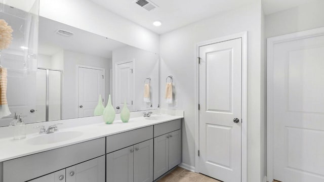 bathroom featuring double vanity, a stall shower, visible vents, and a sink