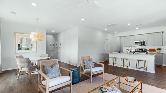 living room featuring baseboards, visible vents, dark wood-type flooring, and recessed lighting