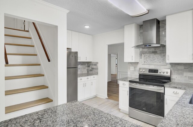 509 Hill St, Moncks Corner, SC 29461 - kitchen with appliances with stainless steel finishes, wall chimney range hood, white cabinets, light stone counters, and a textured ceiling