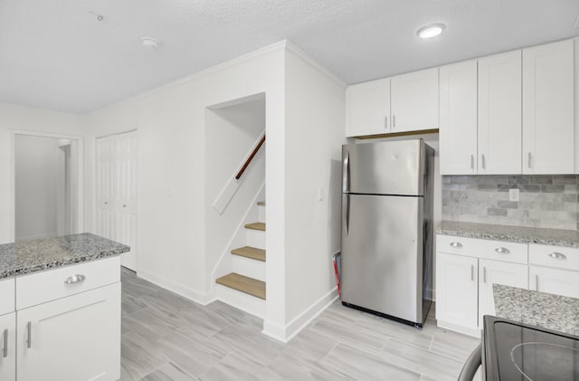 509 Hill St, Moncks Corner, SC 29461 - kitchen featuring freestanding refrigerator, white cabinetry, light stone countertops, backsplash, and electric range