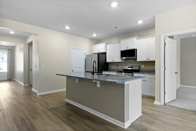 318 Bering Ln, Summerville, SC 29486 - kitchen featuring appliances with stainless steel finishes, a center island with sink, wood finished floors, and white cabinetry