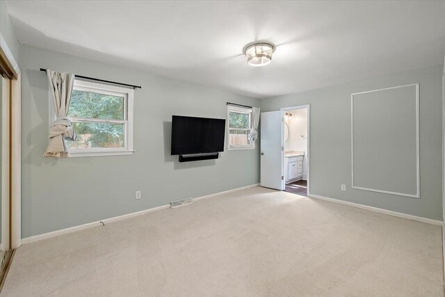 unfurnished bedroom featuring connected bathroom and light colored carpet