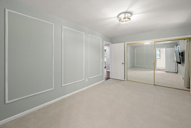 unfurnished bedroom with a closet, light colored carpet, and multiple windows