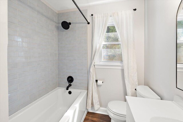 full bathroom featuring hardwood / wood-style flooring, vanity, shower / tub combo with curtain, and toilet