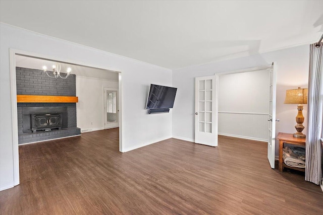 unfurnished living room featuring dark hardwood / wood-style flooring, a fireplace, a notable chandelier, and brick wall