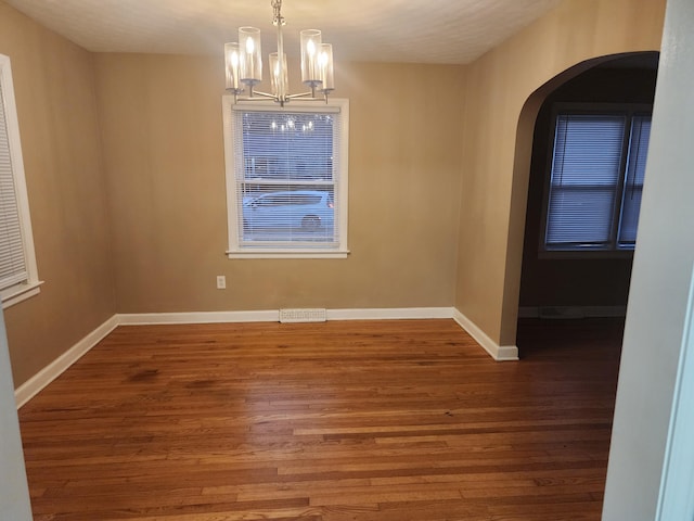 unfurnished dining area featuring wood-type flooring and a notable chandelier