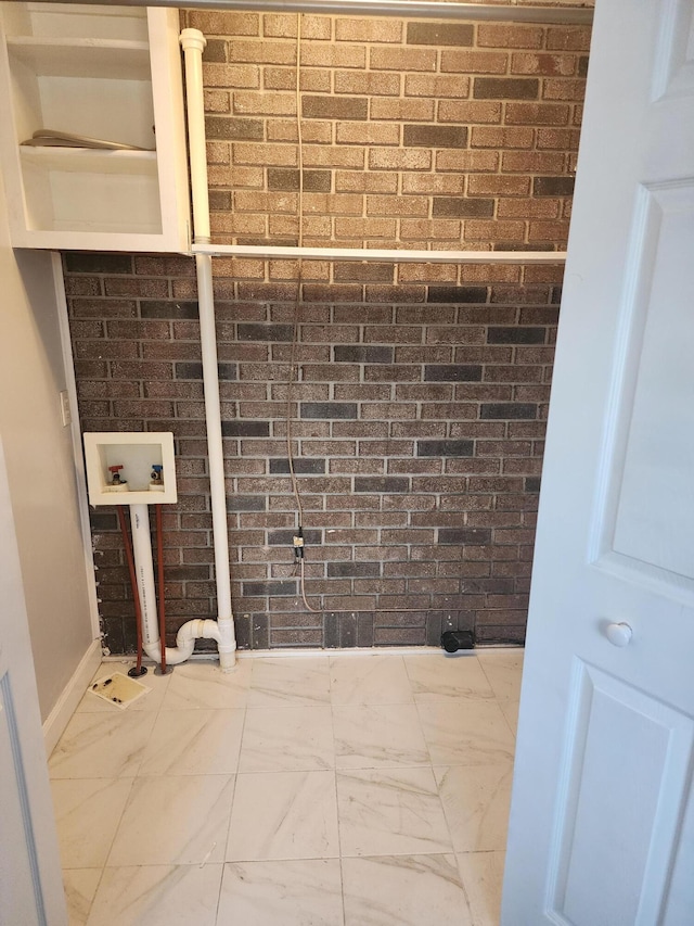 laundry area featuring hookup for a washing machine and brick wall