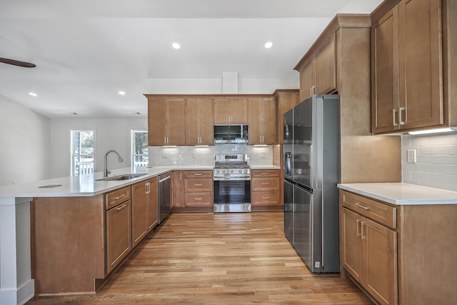 kitchen with brown cabinets, a sink, stainless steel appliances, and light countertops